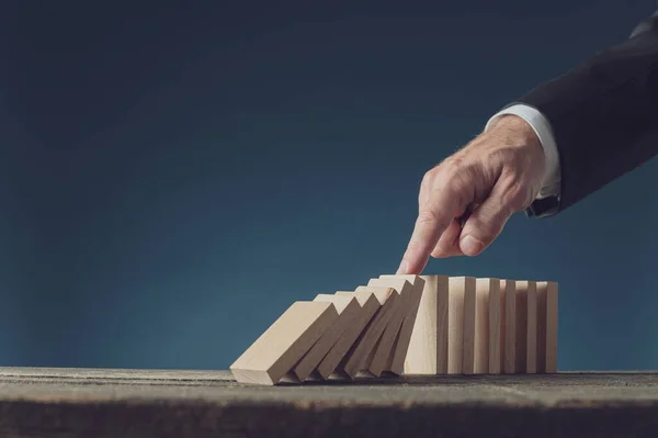 Business crisis manager stopping collapsing dominos with his fin — Stock Photo, Image