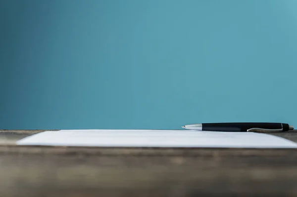 Contrato ou documento com uma caneta deitada sobre uma mesa de madeira texturizada — Fotografia de Stock