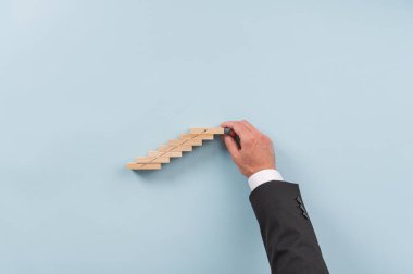 Bir iş adamının eli yukarı bakan bir okla tahta çiviler inşa ediyor. İş vizyonu ve girişimin kavramsal görüntüsü.