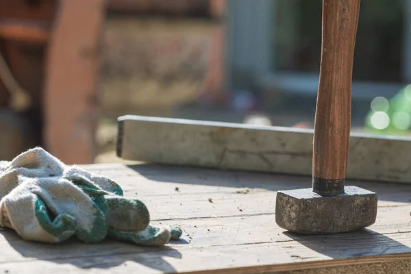 Mallet, protective gloves and label placed on wooden board in a construction site.