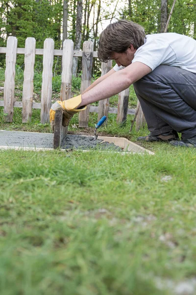 裏庭の穴に注ぎたてのセメントをレベリング若い男の低角度ビューには ダイプロジェクトで — ストック写真