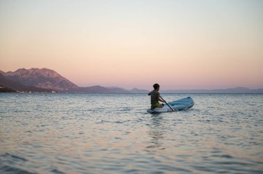 Çocuk yemek masasının arkasında oturuyor ve onu kürekle çeviriyor..