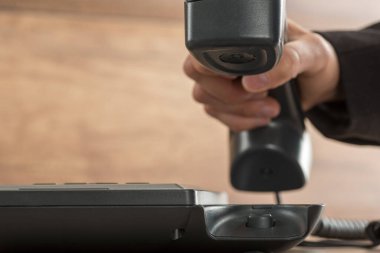 İş adamının siyah bir sabit telefon ahizesini kaldırma ya da kapatma görüntüsü.