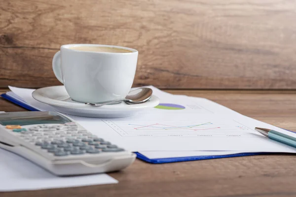 Witte Kop Koffie Bovenop Papierwerk Vol Grafieken Naast Een Rekenmachine — Stockfoto