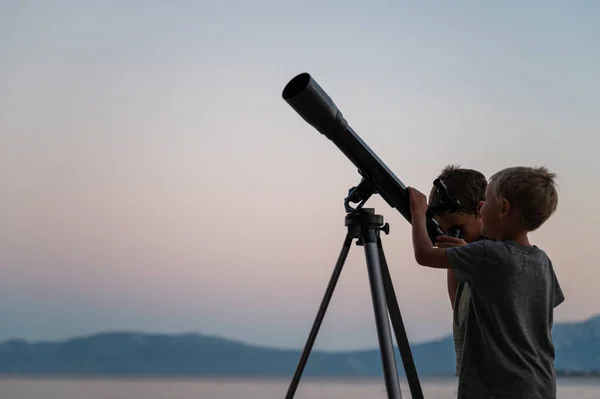 两个兄弟 蹒跚学步的男孩 在一个美丽的夏夜 在海边用望远镜望着星星 — 图库照片