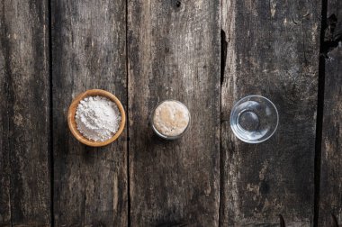 Ev yapımı ekmek için malzemelerle dolu üç fincanın üst görüntüsü - su, mayalı ekmek ve un..