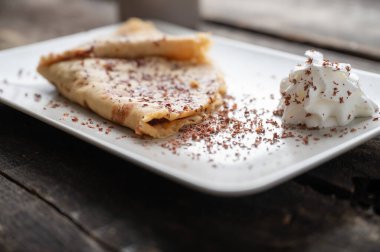 Ev yapımı vejetaryen krepinin düşük açılı görüntüsü çikolata parçacıkları ve çırpılmış kremayla dolu ve katlanmış..