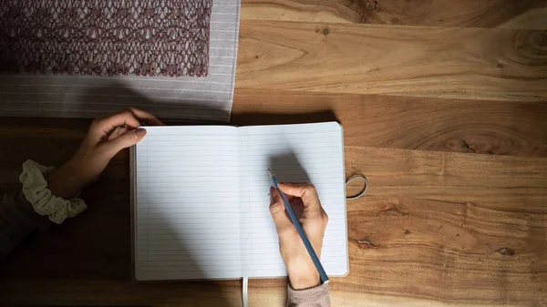 木製の机の上にノートを書き 作る女性の上のビュー — ストック写真