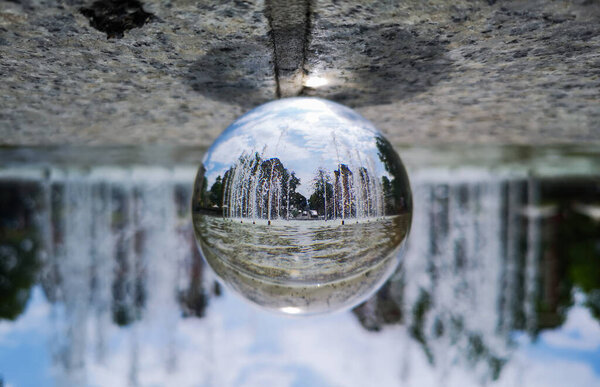 Big city fountain reflected in crystal glassy lens ball