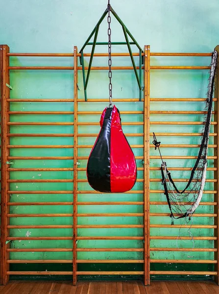 Black and red punching bag in front of wooden ladders in gym