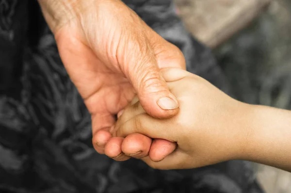 Manos de una niña y una abuela. Manos de un niño pequeño sosteniendo al anciano, concepto del Día Mundial de la Bondad — Foto de Stock