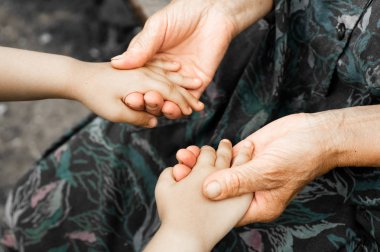 Küçük bir kız ve eski bir anneanne elinde. Küçük bir çocuk yaşlı bir adam, dünya nezaket günü kavramı tutan eller