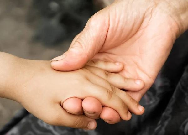 Hands of a little girl and an old grandmother. Hands of a little kids holding elderly man, World Kindness Day concept — Stock Photo, Image