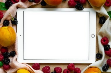 Tablet ahşap arka plan üzerinde taze organik meyve ile çevrili. Sağlıklı gıda, yukarıdan görünüm. Metin için yer. Kopya alanı