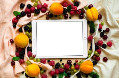 Tablet ahşap arka plan üzerinde taze organik meyve ile çevrili. Sağlıklı gıda, yukarıdan görünüm. Metin için yer. Kopya alanı