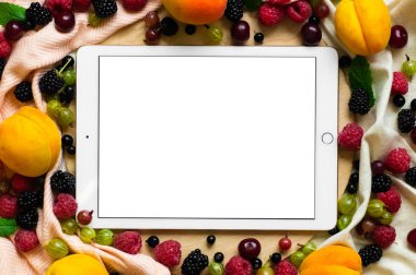 Tablet ahşap arka plan üzerinde taze organik meyve ile çevrili. Sağlıklı gıda, yukarıdan görünüm. Metin için yer. Kopya alanı