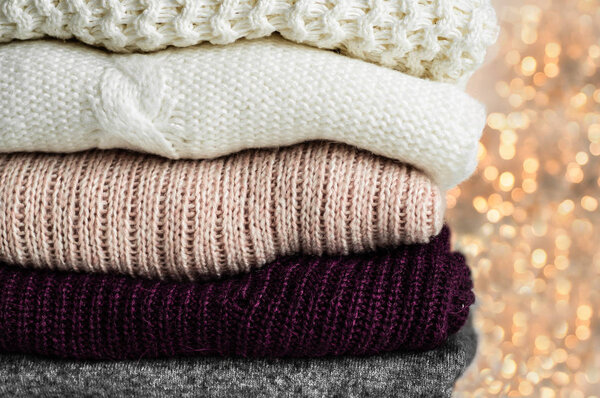Теплые свитера. Куча трикотажной одежды на теплом фоне, свитера, трикотаж, место для текста, осенняя зимняя концепция. Копировальное пространство

