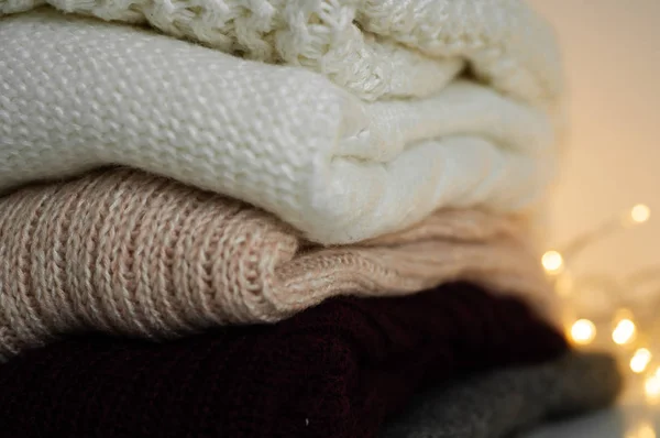 Warm sweaters. Pile of knitted clothes on warm background, sweaters, knitwear, space for text, Autumn winter concept. Copy Space