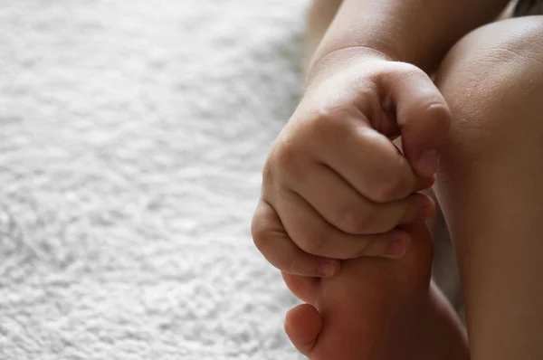 A small child holds his or her arm on a woolen white background. Skin. Leg. Concepts for children. Parent help assistance concept — Stock Photo, Image