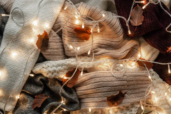 Arka plan ile sıcak kazak. Sonbahar yaprakları ve bir çelenk, sıcak arka plan, triko, metin, sonbahar kış konsepti için yer ile örme elbise yığını. Kopya alanı.