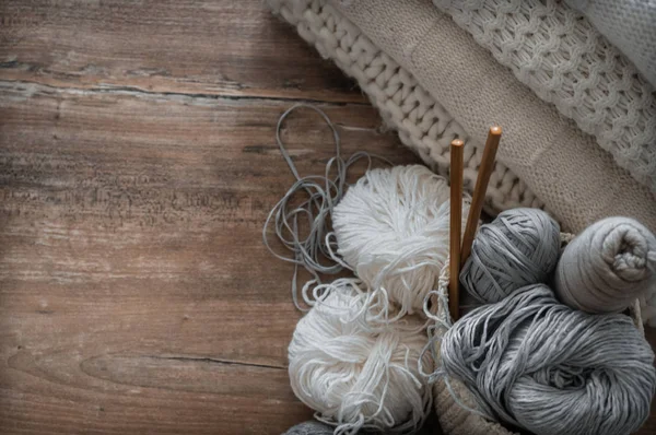 Een geweven mand met witte en grijze draad voor breien en op breinaalden. Witte truien en garens voor close-up breien. Winter — Stockfoto