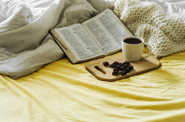 Morning Coffee With Bible Illuminated By Sunlight. Cup of coffee with Christian Bible. White bedroom. Chocolate and coffee cup.