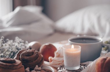 Bir tepsi çay, kruvasan, meyve, çiçek yatakta kahvaltı. Sabah. Rahat daire. Romantizm. parlak arka plan düzen. bir gün izin