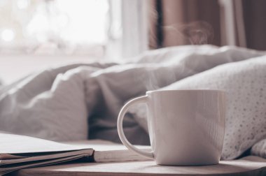 Bir tepsi çay, kruvasan, meyve, çiçek yatakta kahvaltı. Kitap metni odak dışında açıktır. Arka plan düzen. bir gün izin