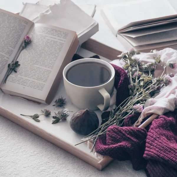Komposisi secangkir teh dan buku yang dibuka tidak dapat dibaca di atas meja kopi di dalam ruangan, dengan ara dan bunga. tutup — Stok Foto