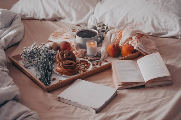 Sarapan di tempat tidur, nampan teh, croissant, buah, bunga. Buka bukunya, teksnya tidak fokus. Latar belakang. hari libur — Stok Foto