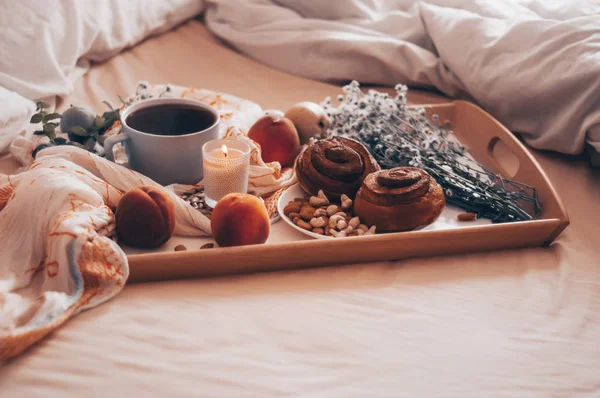 อาหารเช้าบนเตียง ถาดชา ครัวซองต์ ผลไม้ ดอกไม้ เช้าจ้ะ อพาร์ทเม้นท์ที่อบอุ่น โรแมนติค รูปแบบพื้นหลังที่สดใส วันหยุด — ภาพถ่ายสต็อก