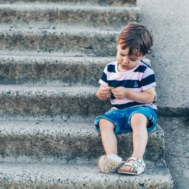 Mutlu çocuk, küçük çocuk görünüyor aşağı, dalgın bakmak ve büyümeleri açık havada elinde tutan. Metin için yer. Retro tonda. Yaz