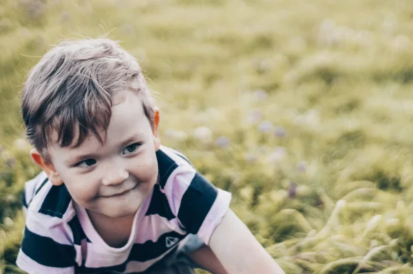 Glada barn, liten pojke ser ner, fundersam look och håller i händerna utväxter utomhus. Utrymme för Text. Retro tonas. Sommar — Stockfoto