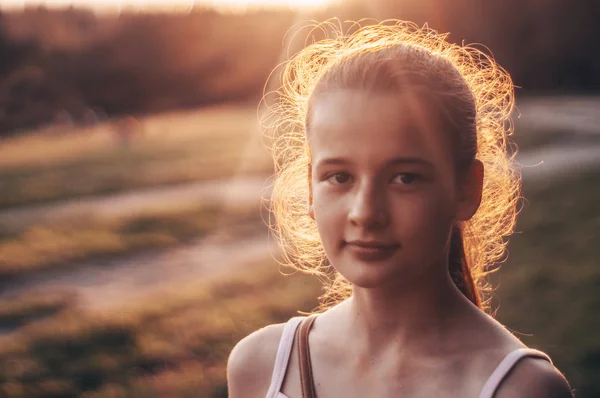 Retrato de menina bonita bonita na luz do sol da noite na natureza. menina desfrutando de verão e tempo ensolarado no prado — Fotografia de Stock