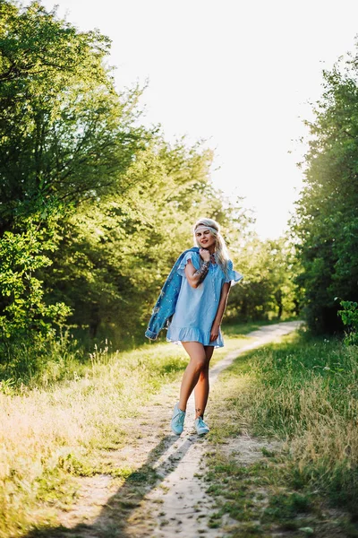 Portréja egy gyönyörű lány, egy kék ruhát, a fejfájás, a mező a naplemente a nyári időszakban. Alkalmi nyári ruhák. Közeli kép: — Stock Fotó