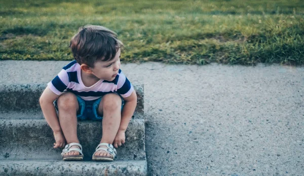 Mutlu çocuk, küçük çocuk görünüyor aşağı, dalgın bakmak ve büyümeleri açık havada elinde tutan. Metin için yer. Retro tonda. Yaz
