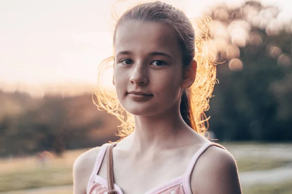 Retrato de una hermosa joven en el sol de la noche en la naturaleza. chica disfrutando del verano y el clima soleado en el prado — Foto de Stock