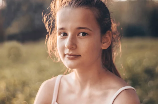 Retrato de menina bonita bonita na luz do sol da noite na natureza. menina desfrutando de verão e tempo ensolarado no prado — Fotografia de Stock