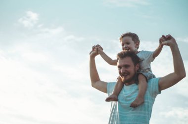 Mutlu çocuk babamla oynuyor. Babam ve oğlum dışarıda. Babası çocuğu sırtında taşıyor. Yaz tarlasında mutlu aile