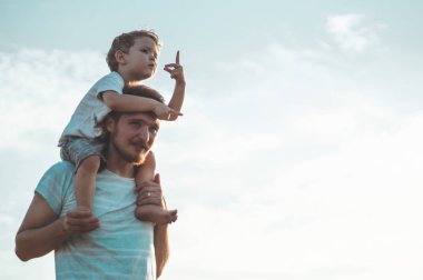 Mutlu çocuk babamla oynuyor. Babam ve oğlum dışarıda. Babası çocuğu sırtında taşıyor. Yaz tarlasında mutlu aile