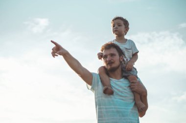 Mutlu çocuk babamla oynuyor. Babam ve oğlum dışarıda. Babası çocuğu sırtında taşıyor. Yaz tarlasında mutlu aile