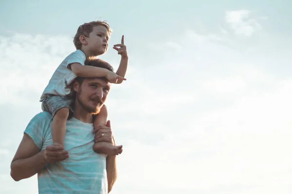 Glückliches Kind, das mit Vater spielt. Vater und Sohn im Freien. Vater trägt Kind auf dem Rücken. glückliche Familie im Sommerfeld — Stockfoto