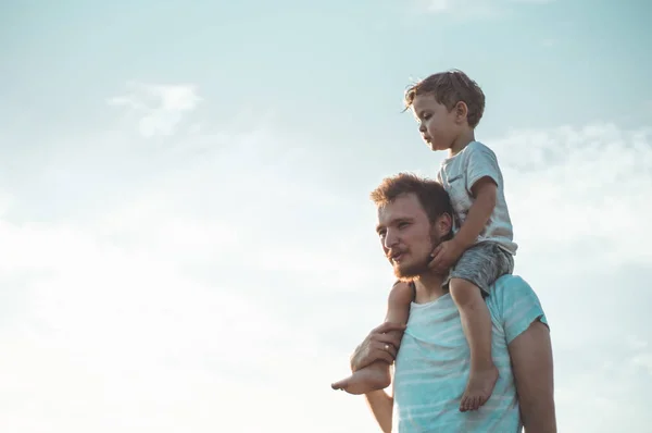 Um miúdo feliz a brincar com o pai. Pai e filho ao ar livre. Pai carregando criança em suas costas. Família feliz no campo de verão — Fotografia de Stock