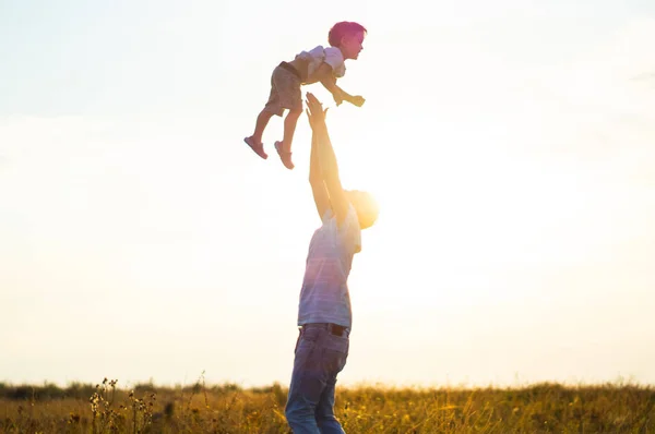 Vater wirft seinen niedlichen kleinen Sohn an die frische Luft. Vatertag: Vater und Sohn spielen und umarmen sich im Freien. — Stockfoto