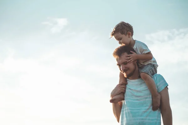 Szczęśliwy dzieciak bawiąc się z ojcem. Tata i syn na zewnątrz. Ojciec niosący dziecko na plecach. Szczęśliwa rodzina w polu letnim — Zdjęcie stockowe