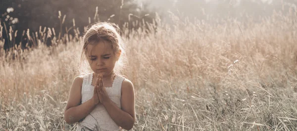 La niña cerró los ojos rezando al atardecer. Manos dobladas en concepto de oración por la fe, la espiritualidad y la religión. Esperanza, concepto . —  Fotos de Stock