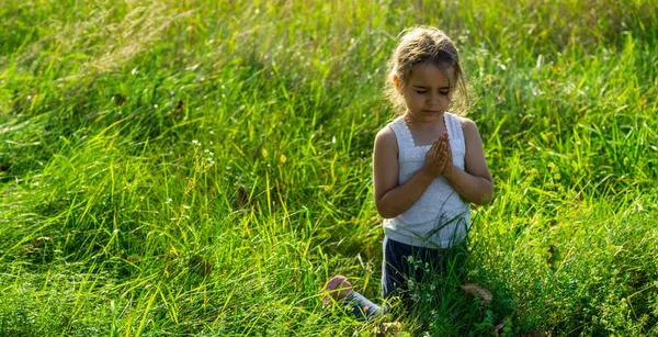 La niña cerró los ojos rezando al atardecer. Manos dobladas en concepto de oración por la fe, la espiritualidad y la religión. Esperanza, concepto . —  Fotos de Stock
