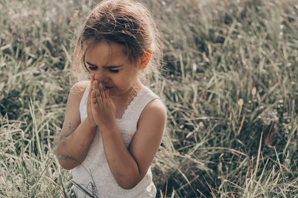 Gadis kecil menutup matanya berdoa saat matahari terbenam. Tangan dilipat dalam konsep doa untuk iman, spiritualitas dan agama. Harapan, konsep . — Stok Foto