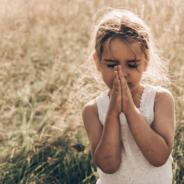 Gadis kecil menutup matanya berdoa saat matahari terbenam. Tangan dilipat dalam konsep doa untuk iman, spiritualitas dan agama. Harapan, konsep . — Stok Foto