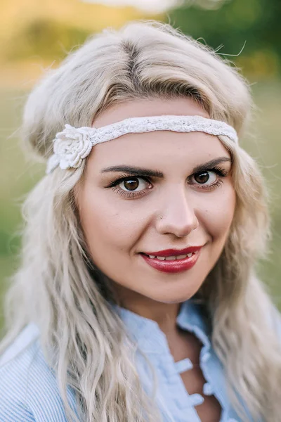 Porträt eines schönen Mädchens in einem blauen Kleid mit Kopfschmerzen auf einem Feld bei Sonnenuntergang im Sommer. lässige Sommerkleidung. Nahaufnahme — Stockfoto